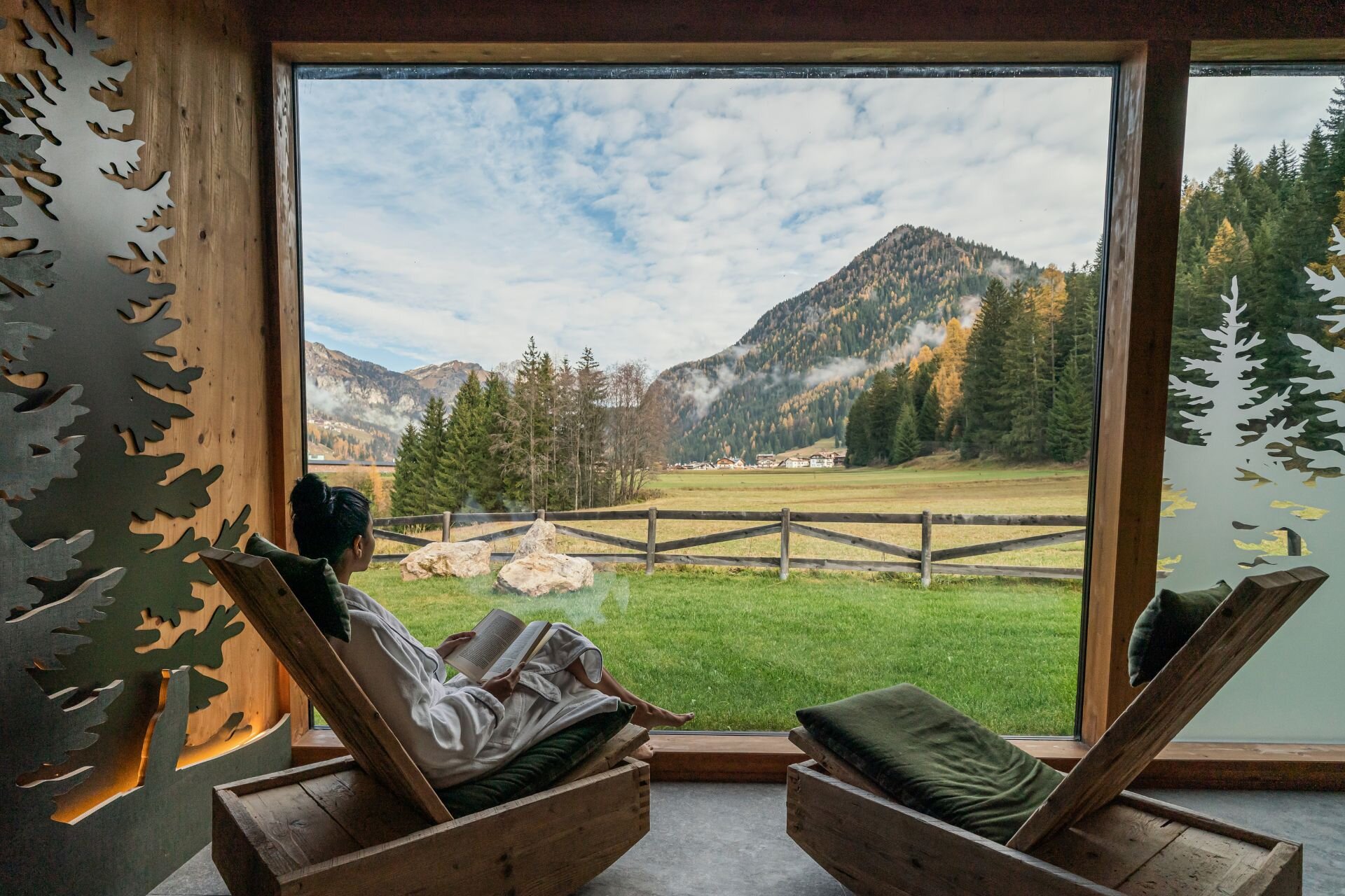 Una donna si rilassa in una sala termale con vista sulle Dolomiti autunnali | © Archivio immagini QCTerme - 2025