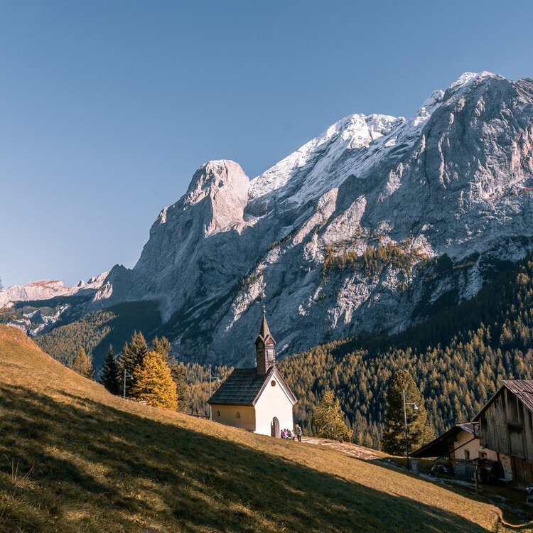Chiesetta in mezzo al bosco autunnale con la Marmolada innevata sullo sfondo | © Archivio Immagini ApT Val di Fassa - Patricia Ramirez